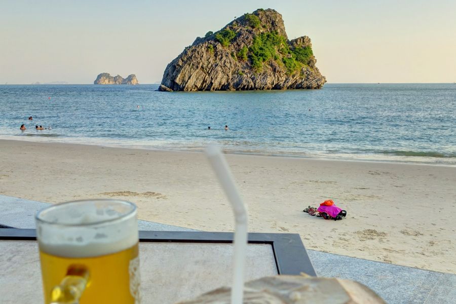 La plage de Cat Ba, l'une des plus belles du Vietnam, offre un littoral accidenté de sable blanc et d'eaux turquoise. Des karsts calcaires se dressent à perte de vue en arrière.
