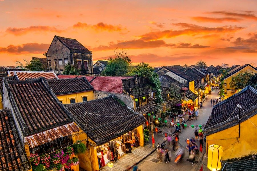 Vue du coucher de soleil sur la vieille ville de Hoi An, avec ses bâtiments jaunes, ses toits de tuiles et ses rues éclairées par des lanternes. C'est une destination incontournable pour un voyage au Vietnam en 2026.