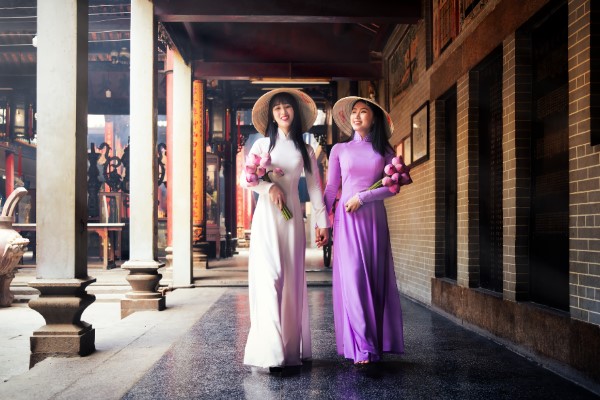 Deux femmes vietnamiennes en Ao Dai tenant des fleurs de lotus. Ce sont des symboles du Vietnam.